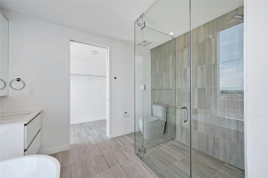 Primary bathroom includes a frameless glass shower, and direct access to a spacious walk-in closet.