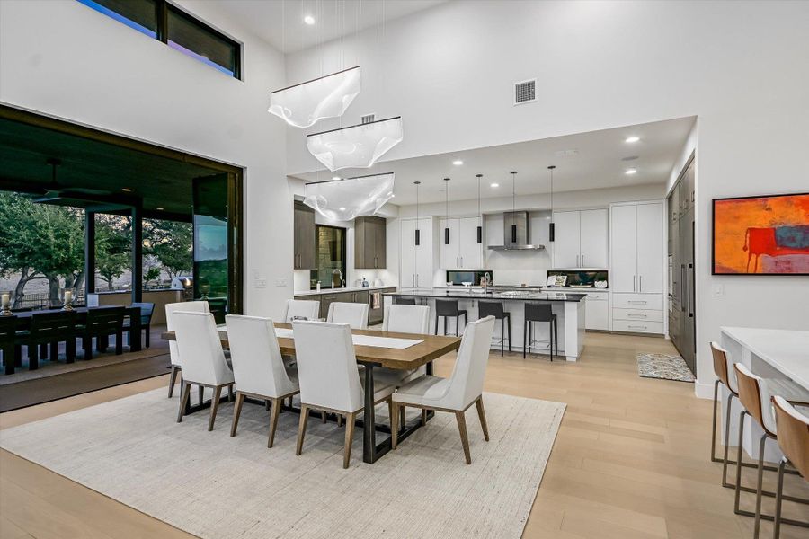 Dining area with a high ceiling, light wood finished floors, and recessed lighting Dining area with a high ceiling, light wood finished floors, and recessed lighting