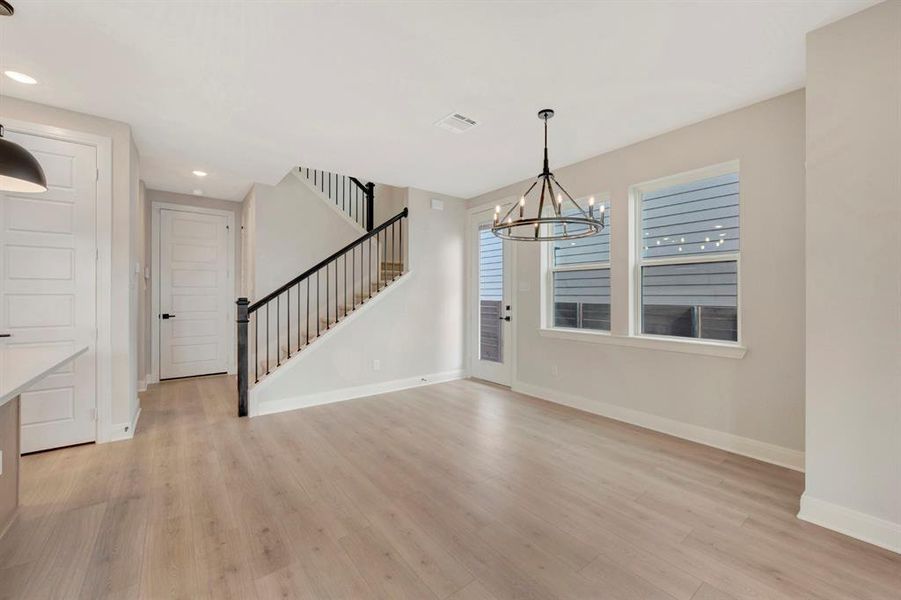 Unfurnished dining area with hanging lights and light wood-type flooring