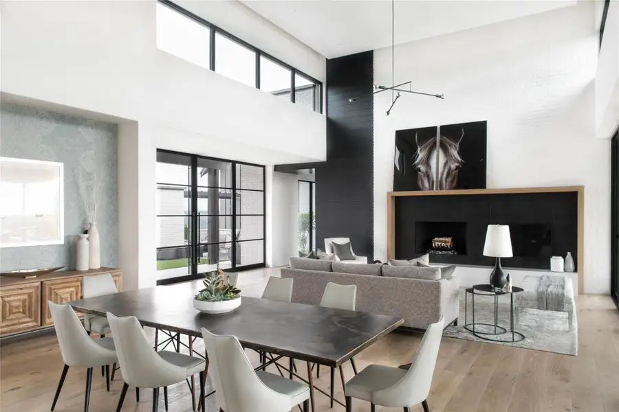 Dining area featuring a fireplace, light wood-type flooring, a towering ceiling, and wallpapered walls