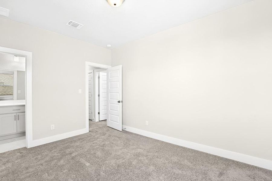 Unfurnished bedroom with light carpet and ensuite bath Unfurnished bedroom with light carpet and ensuite bath