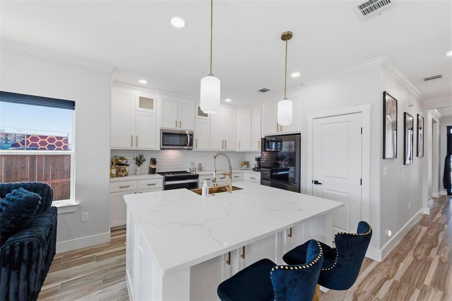Kitchen featuring ornamental molding, white cabinets, an island with sink, a kitchen breakfast bar, and range with electric stovetop