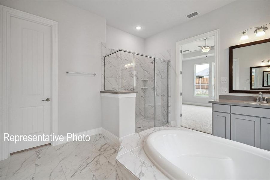 Soaking tub with surrounding tile, walk-in shower with glass enclosure and marble-finish tile, dual vanity with undermount sinks, wood-frame mirror, and recessed lighting