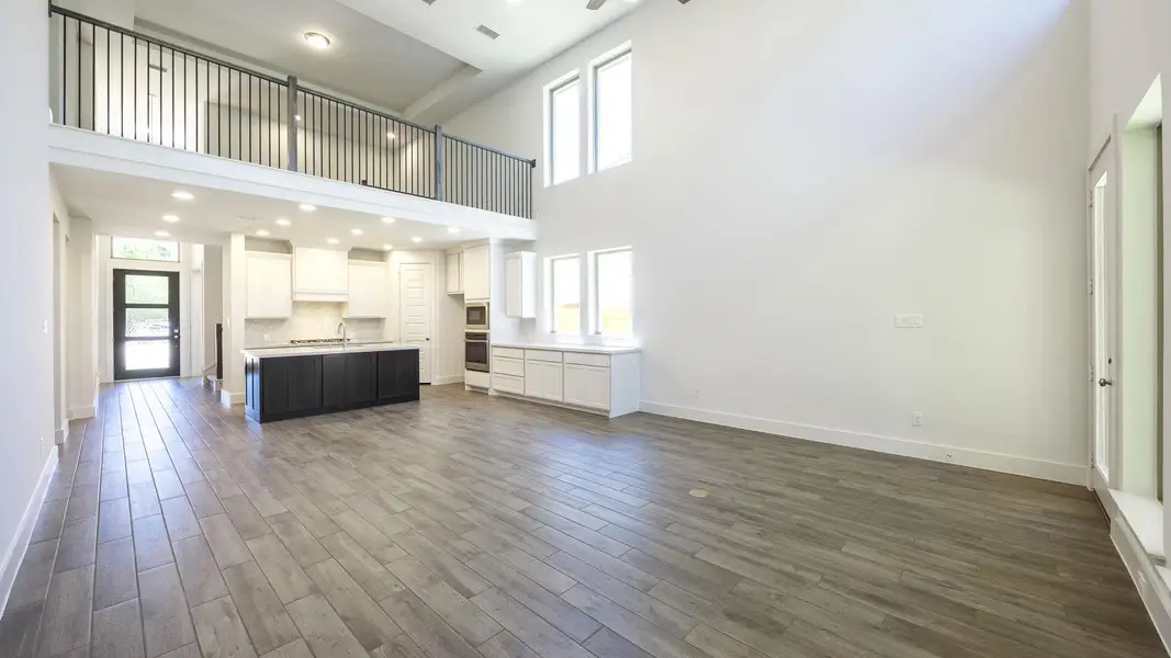 Unfurnished living room featuring dark wood finished floors, a high ceiling, baseboards, and visible vents Unfurnished living room featuring dark wood finished floors, a high ceiling, baseboards, and visible vents
