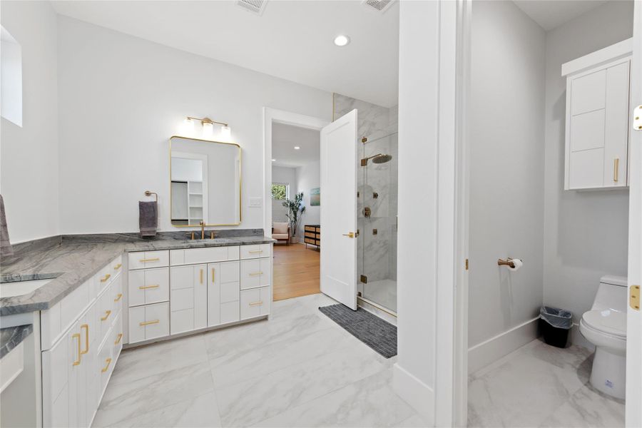 The luxurious primary bath combines timeless elegance with everyday function, featuring dual marble-topped vanities, custom cabinetry, designer brass hardware, and an oversized walk-in shower with premium marble surrounds. The luxurious primary bath combines timeless elegance with everyday function, featuring dual marble-topped vanities, custom cabinetry, designer brass hardware, and an oversized walk-in shower with premium marble surrounds.