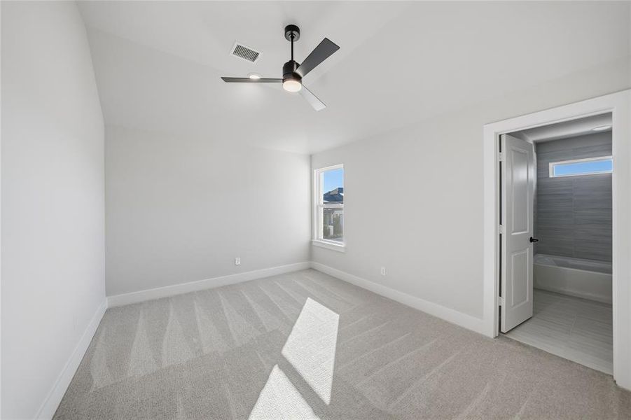 Unfurnished bedroom featuring light colored carpet, ceiling fan, and ensuite bathroom