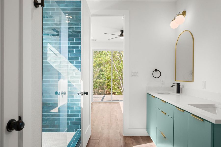 Full bathroom with a shower stall, double vanity, and light wood-type flooring