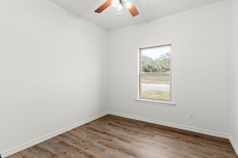 Unfurnished room featuring baseboards, a ceiling fan, and wood finished floors Unfurnished room featuring baseboards, a ceiling fan, and wood finished floors
