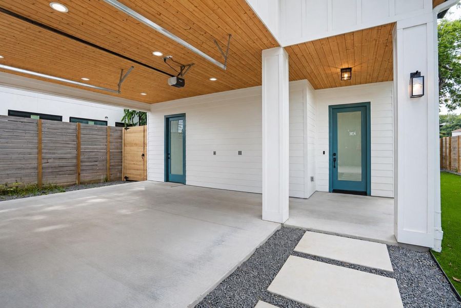 A striking contemporary residence boasts a carport and two prominent turquoise entry doors.