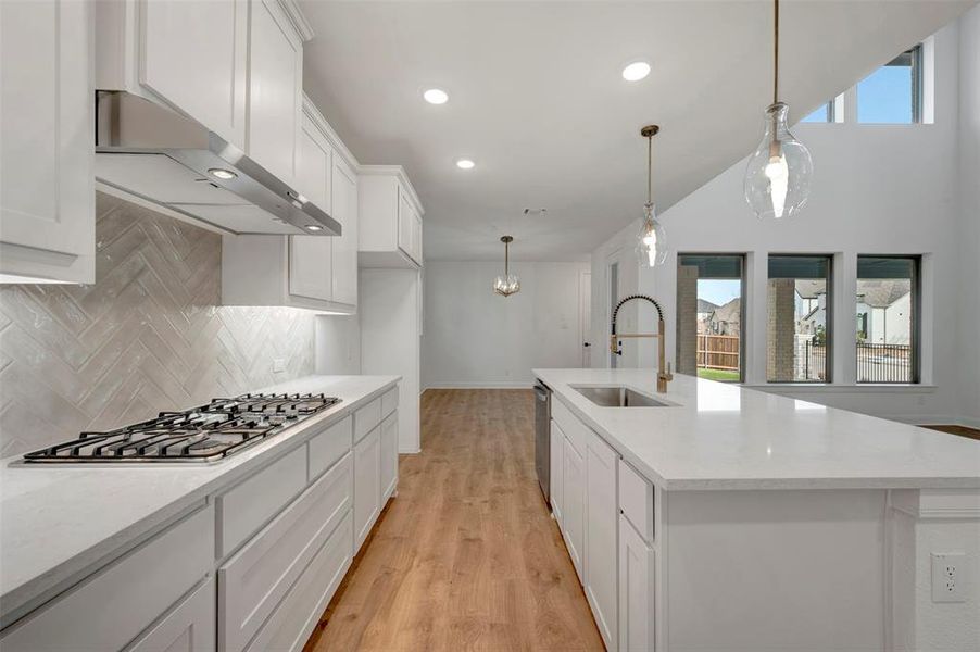 Kitchen with white cabinetry, light wood finished floors, light stone countertops, and extractor fan