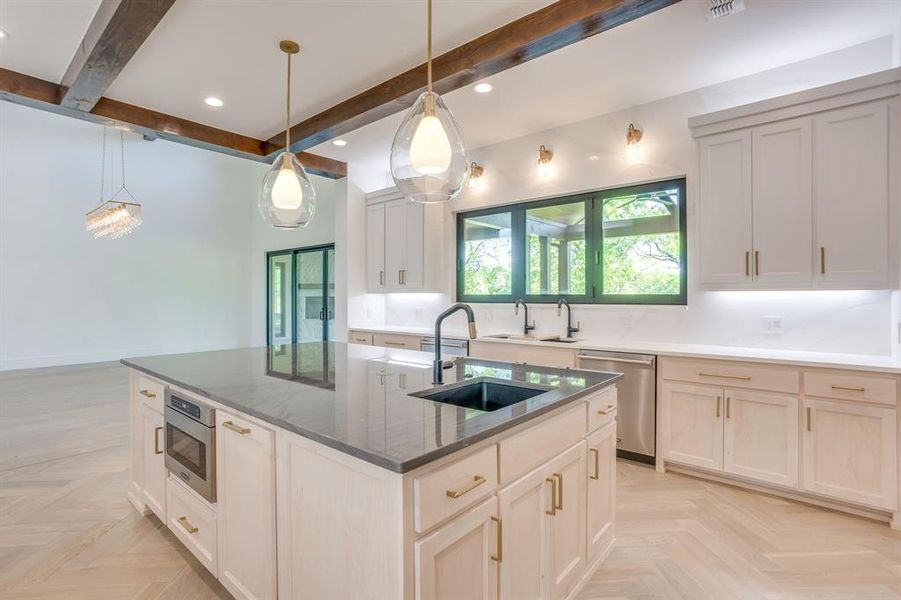 Kitchen featuring parquet flooring, decorative light fixtures, stainless steel dishwasher, a kitchen island with sink, and beam ceiling