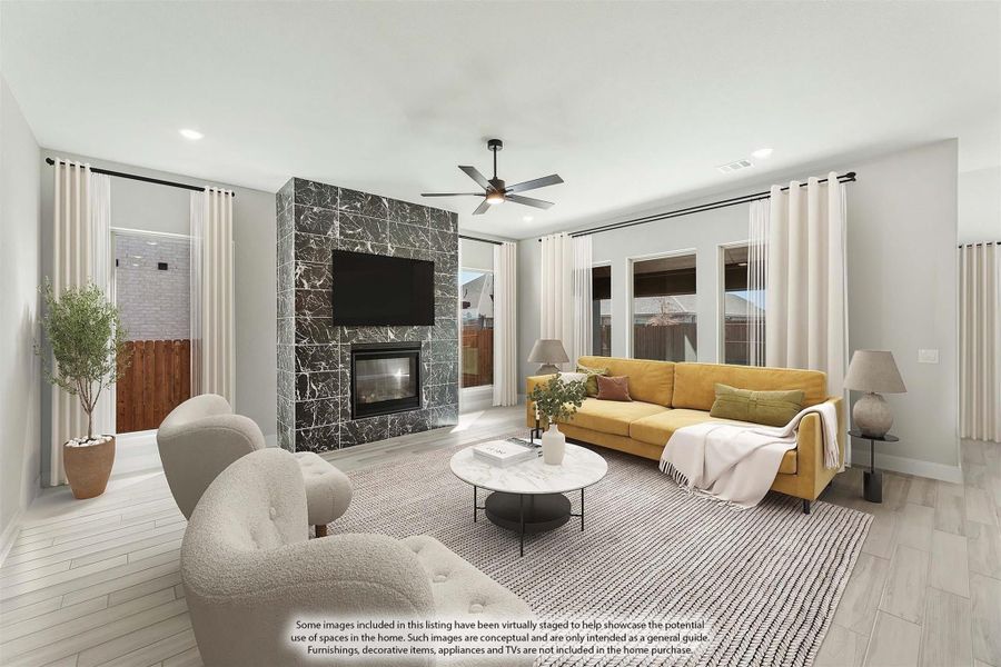 Living room with dark marble fireplace, ceiling fan, yellow sofa, and light wood floors Living room with dark marble fireplace, ceiling fan, yellow sofa, and light wood floors