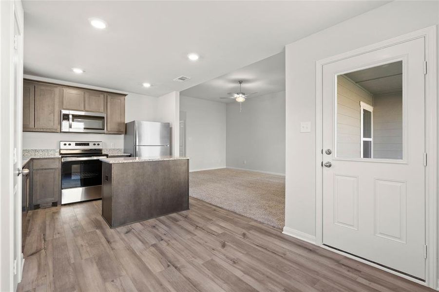 Kitchen with stainless steel appliances, a center island, ceiling fan, light wood-style floors, and recessed lighting