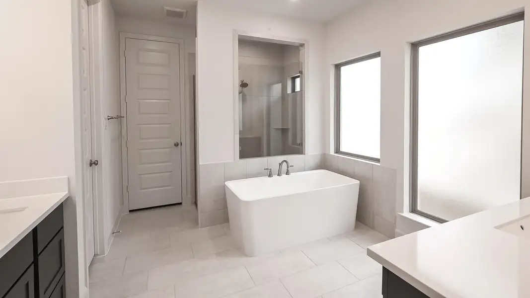 Bathroom with vanity, a shower stall, a soaking tub, light tile patterned floors, and tile walls