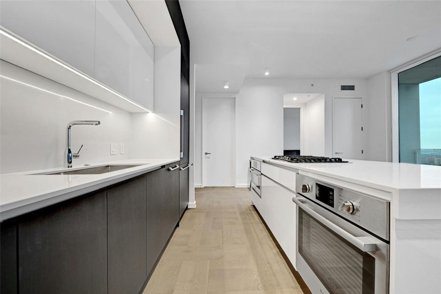 Modern kitchen with sleek cabinetry, integrated Bosch® appliances and a waterfall island with gas cooktop. Photo is model unit #2406.