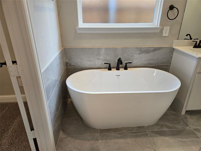 Full bathroom with a soaking tub, vanity, wainscoting, and tile walls Full bathroom with a soaking tub, vanity, wainscoting, and tile walls