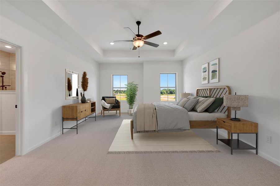 Spacious room featuring tray ceilings with a ceiling fan, two large windows, light-toned carpeting, and a doorway opening to a bathroom with a tiled shower Spacious room featuring tray ceilings with a ceiling fan, two large windows, light-toned carpeting, and a doorway opening to a bathroom with a tiled shower