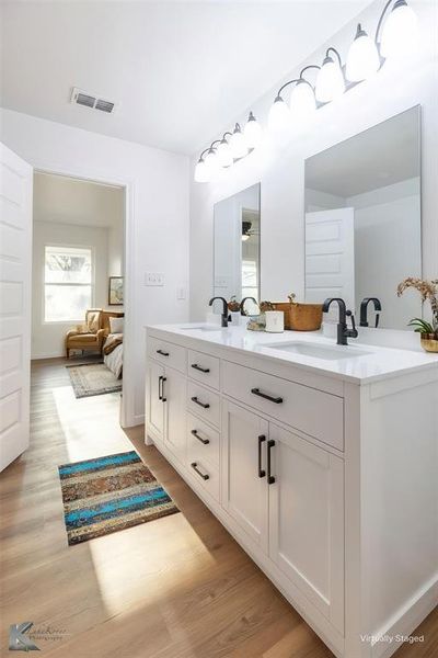 Bathroom with double vanity, light wood finished floors, and connected bathroom