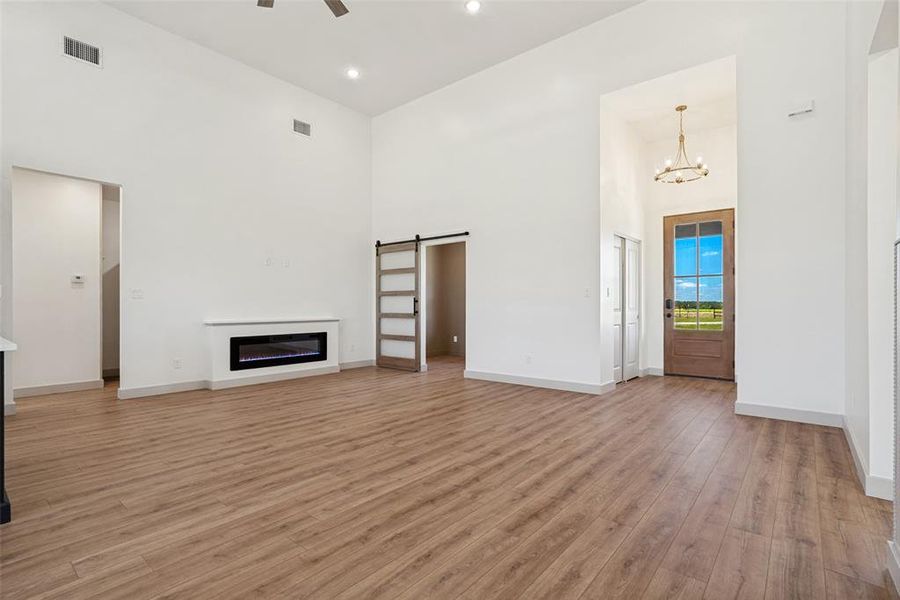 Spacious living area featuring high ceilings, wood-finish flooring, and a built-in electric fireplace