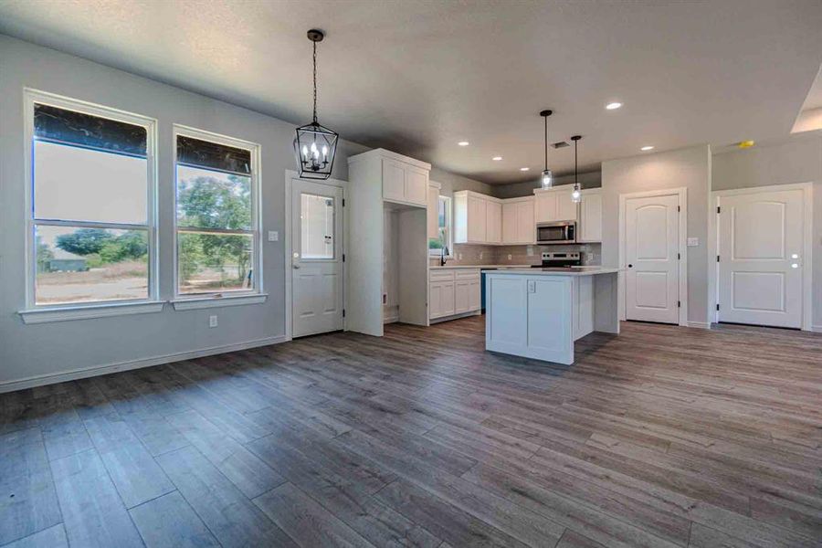 Kitchen with white cabinetry, a chandelier, light countertops, dark wood-style floors, and pendant lighting Kitchen with white cabinetry, a chandelier, light countertops, dark wood-style floors, and pendant lighting