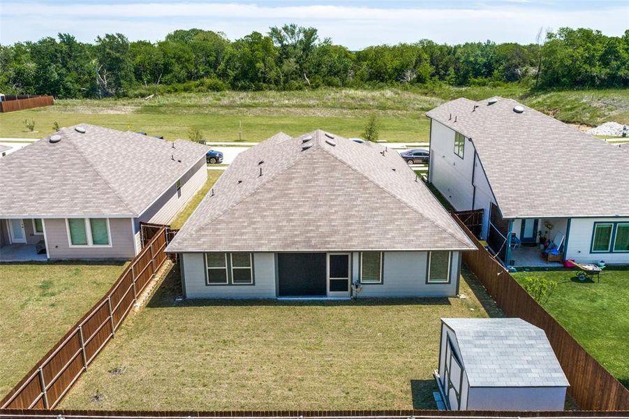 Rear exterior featuring a screened patio, fenced yard with a storage shed, and mature tree line beyond the property Rear exterior featuring a screened patio, fenced yard with a storage shed, and mature tree line beyond the property