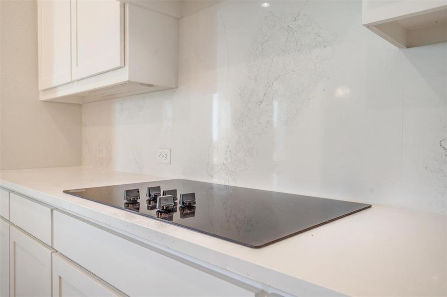 Kitchen featuring black electric stovetop and white cabinets