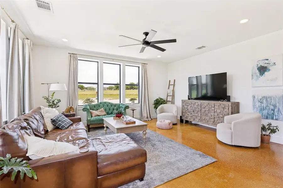 Spacious living area featuring high ceilings, recessed lighting, and a modern ceiling fan Spacious living area featuring high ceilings, recessed lighting, and a modern ceiling fan
