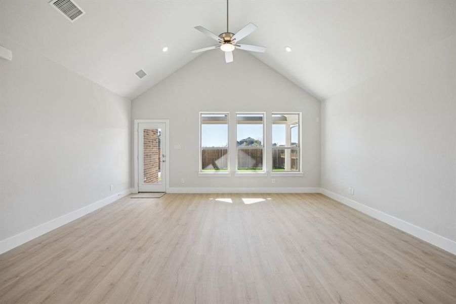 Unfurnished room featuring high vaulted ceiling, light wood finished floors, ceiling fan, and recessed lighting