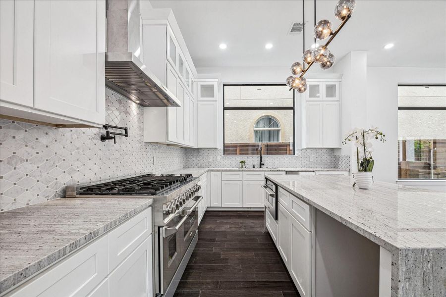 A second kitchen perspective showcases a dramatic chandelier that enhances the space with architectural presence and upscale appeal.