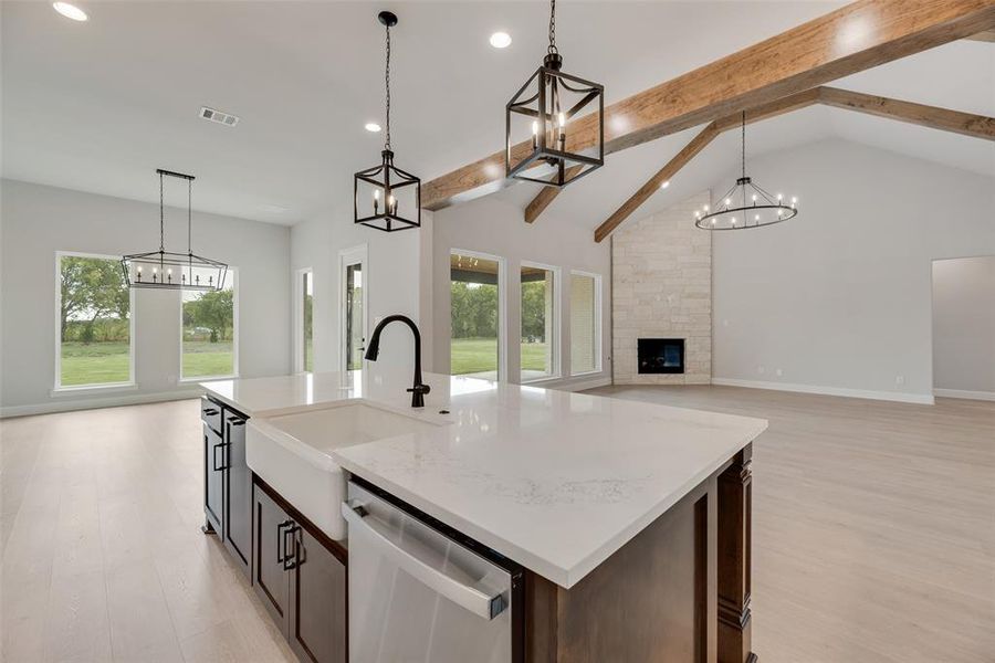 Kitchen with beamed ceiling, a chandelier, open floor plan, stainless steel dishwasher, and decorative light fixtures