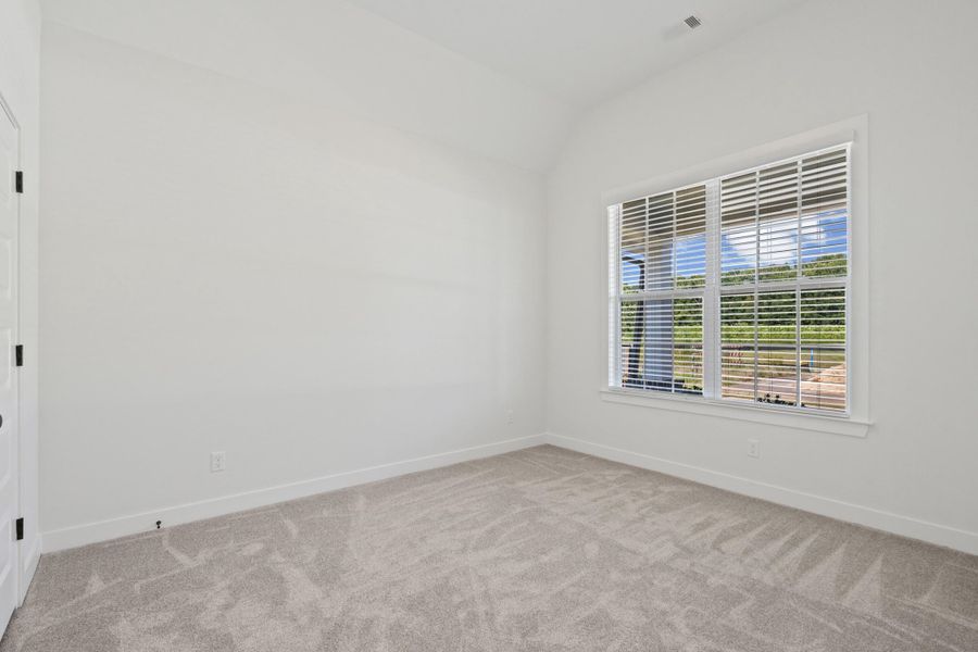 Bright interior space with soft gray carpeting, a large window with white blinds, and a white interior door with black hardware Bright interior space with soft gray carpeting, a large window with white blinds, and a white interior door with black hardware