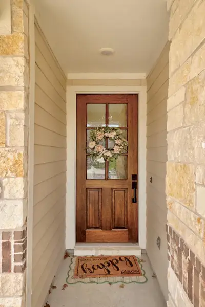 Front entry featuring a paneled wood door with upper glass inserts, a black handle set, and a simple white trim surround