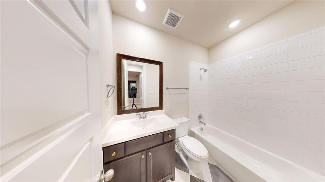 Full bathroom with toilet, tiled shower / bath combo, and vanity