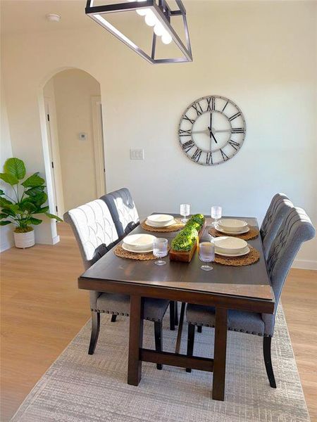 Dining area with arched walkways, light wood-type flooring, and a chandelier