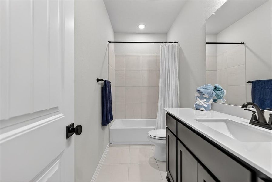 Full bathroom featuring vanity, shower / bathtub combination with curtain, and light tile patterned floors Full bathroom featuring vanity, shower / bathtub combination with curtain, and light tile patterned floors