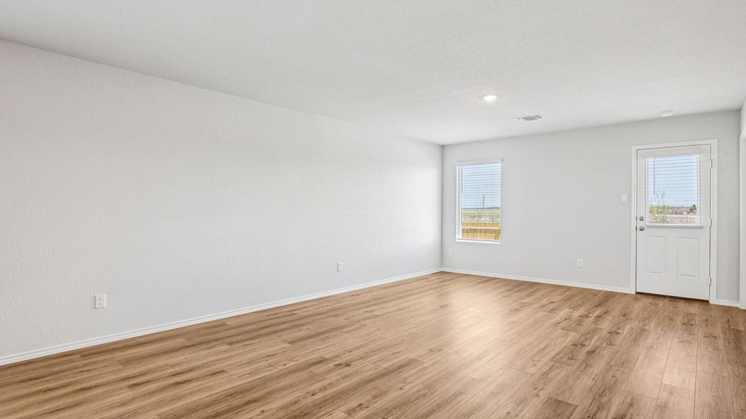 Spacious interior room featuring wood-finish flooring, white baseboards, and neutral wall tones Spacious interior room featuring wood-finish flooring, white baseboards, and neutral wall tones