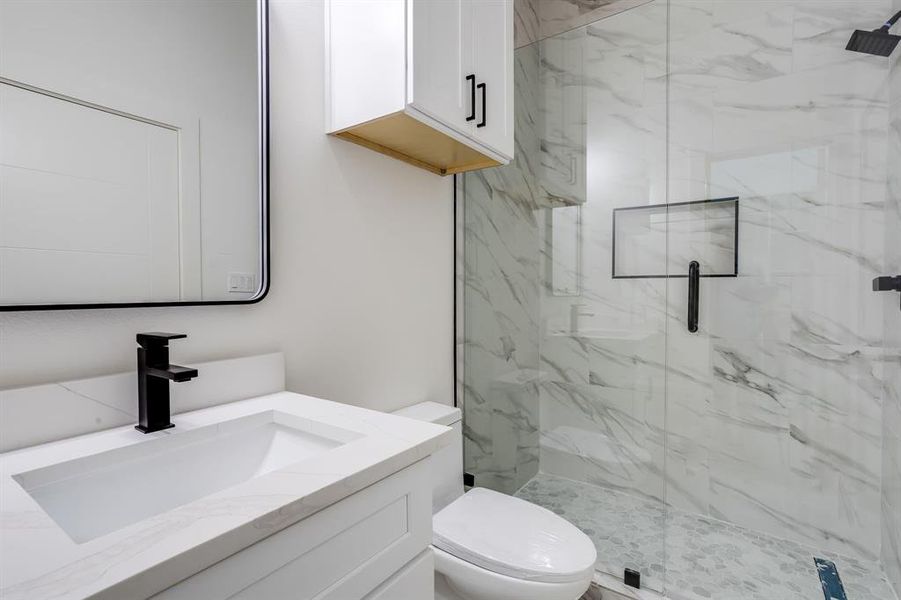 Full bath featuring vanity and a marble finish shower