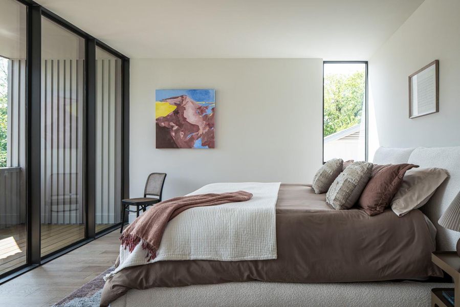 Bedroom featuring wood finished floors, floor to ceiling windows, and access to exterior
