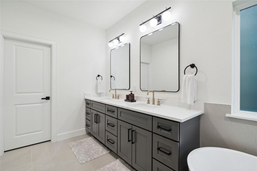 Experience elegance and practicality in this luxurious bathroom, featuring expansive quartz countertops with his-and-hers sinks, ample drawer storage, and generous cabinet space. Designed for ultimate comfort and organized living.
