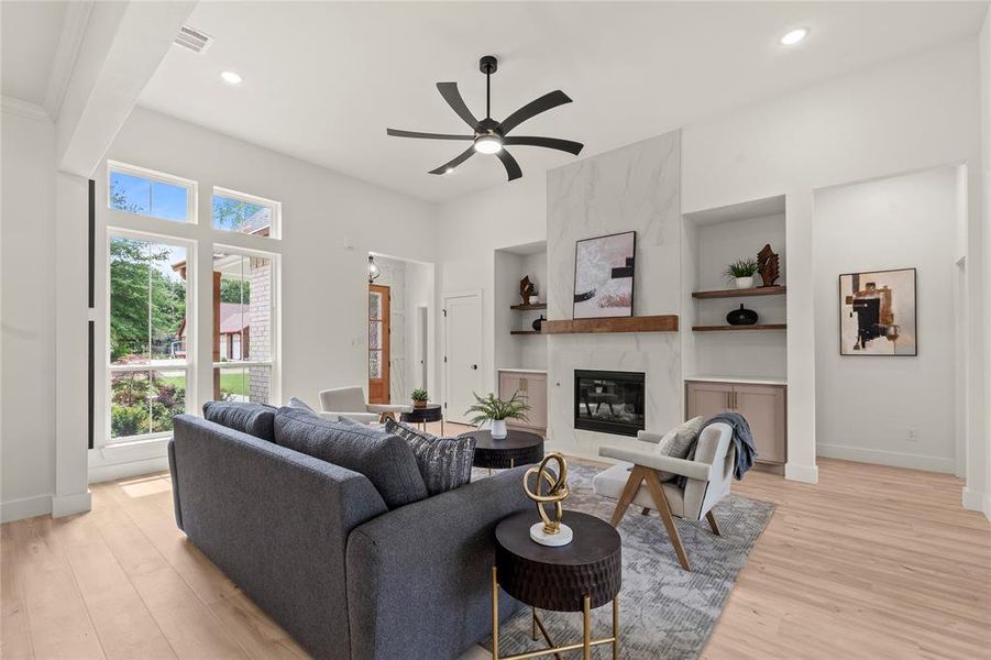 Living room featuring built in features, plenty of natural light, light wood-type flooring, a ceiling fan, and recessed lighting Living room featuring built in features, plenty of natural light, light wood-type flooring, a ceiling fan, and recessed lighting