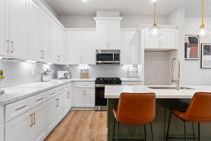 A composition of texture and tone, where a bold accent island grounds the space. Brass detailing, herringbone tilework, and integrated lighting add dimension, while soft close cabinetry reinforces a seamless finish.