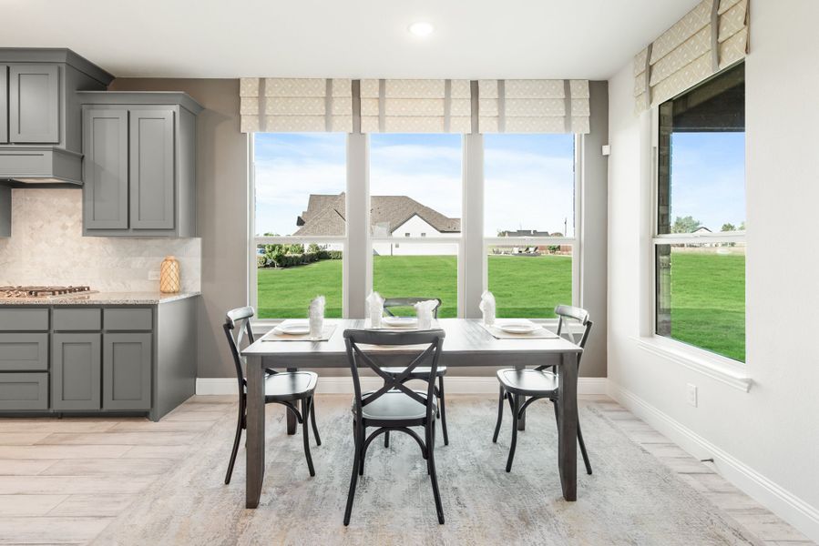 Breakfast nook with four-chair dining table, large windows, and gray kitchen cabinets nearby