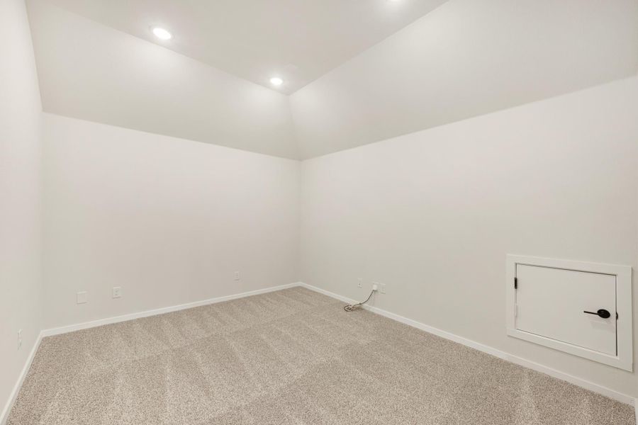 Empty room with beige carpet, white walls, recessed lighting, and a small access panel on the wall