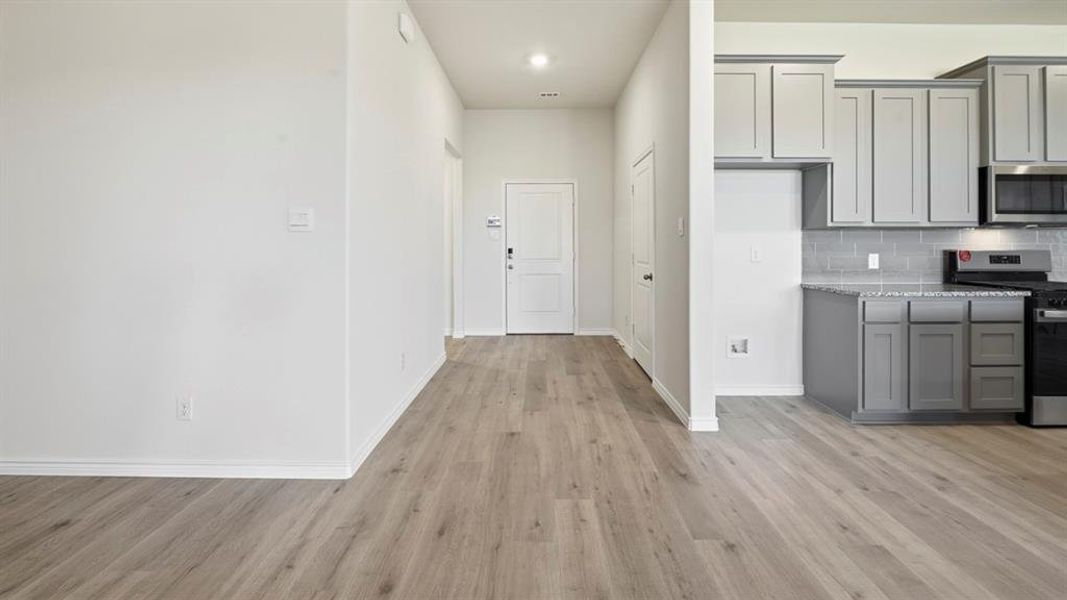 Kitchen featuring gray cabinetry, stainless steel appliances, light stone countertops, and light wood finished floors Kitchen featuring gray cabinetry, stainless steel appliances, light stone countertops, and light wood finished floors