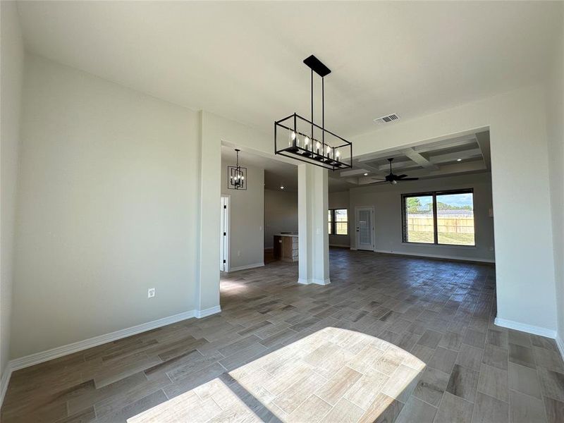 Unfurnished dining area with coffered ceiling, a chandelier, beam ceiling, wood finish floors, and a ceiling fan