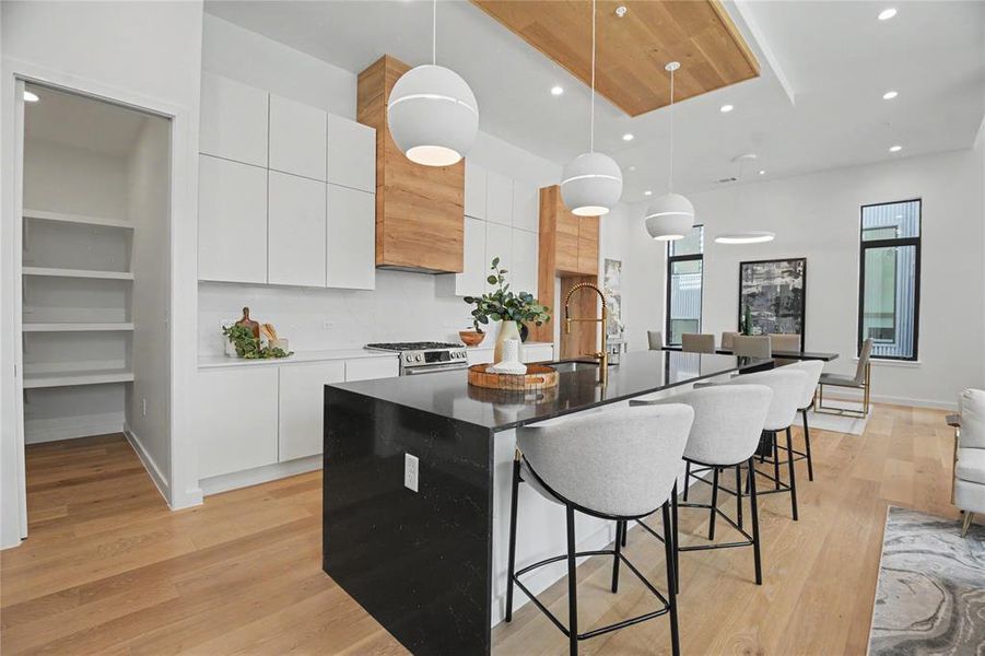 Two tone cabinetry, oversized pendant lighting, and spacious waterfall quartz countertops, sets the tone for modern elegance.