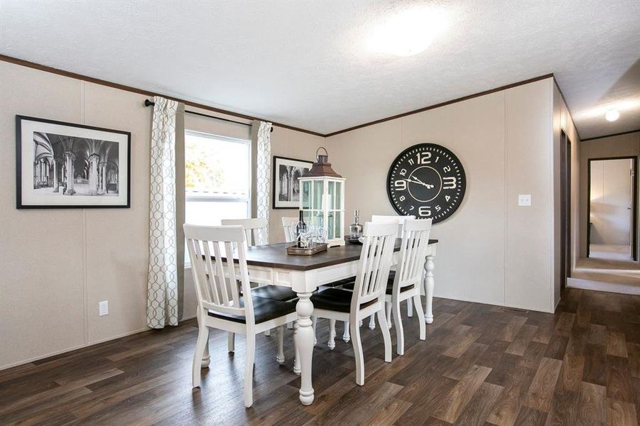 Dining space featuring a textured ceiling, ornamental molding, and dark wood-type flooring