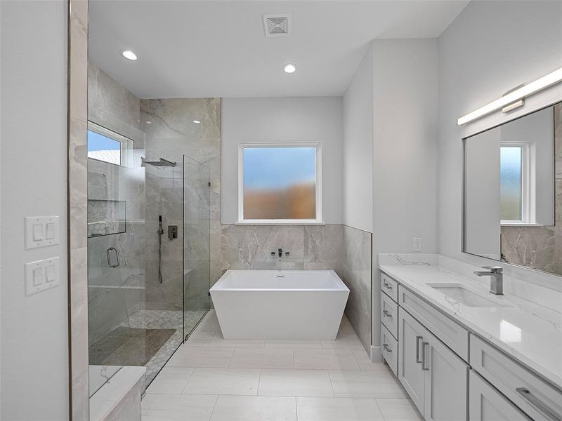 Primary Bathroom featuring plus walk in shower, tile walls, vanity, and tile patterned floors