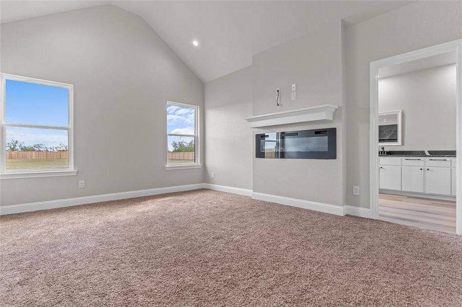 Unfurnished living room with high vaulted ceiling, light carpet, and recessed lighting