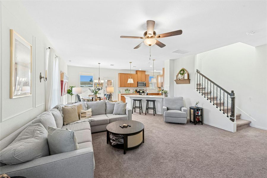 A cozy living area filled with natural light, featuring a gas fireplace flanked by decorative built-ins. This inviting space also includes carpet flooring and a ceiling fan, creating a warm and comfortable atmosphere perfect for everyday living and relaxation.
